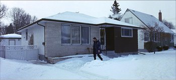 Movie still from “Fear X” (2003), directed by Nicolas Winding Refn – A person walking in the snow near a house; Wide shot, Low angle