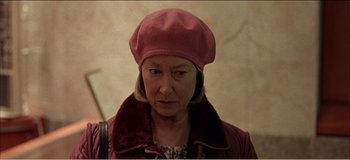 Movie still from “Fear X” (2003), directed by Nicolas Winding Refn – An older woman wearing a pink hat and a red jacket; Close Up shot, Over the shoulder angle