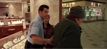 Movie still from “Fear X” (2003), directed by Nicolas Winding Refn – A man and a woman standing in front of a woman; Medium shot, Over the shoulder angle