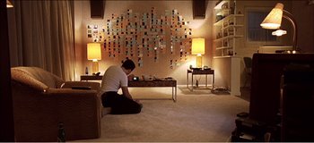 Movie still from “Fear X” (2003), directed by Nicolas Winding Refn – A woman sitting on the floor looking at her cell phone; Wide shot, Low angle