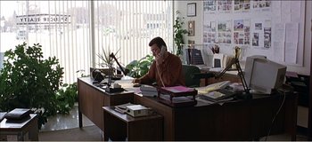 Movie still from “Fear X” (2003), directed by Nicolas Winding Refn – A man sitting at a desk talking on the phone; Wide shot, High angle