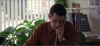 Movie still from “Fear X” (2003), directed by Nicolas Winding Refn – A man talking on a phone while sitting at a table; Close Up shot, High angle