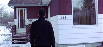 Movie still from “Fear X” (2003), directed by Nicolas Winding Refn – A man standing in front of a house with the number 1 3 2 9 on it; Medium shot, Low angle