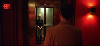Movie still from “Fear X” (2003), directed by Nicolas Winding Refn – A woman standing in an elevator looking in the mirror; Medium shot, Low angle