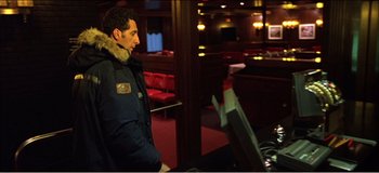 Movie still from “Fear X” (2003), directed by Nicolas Winding Refn – A man standing in front of a table in a restaurant; Medium shot, Over the shoulder angle