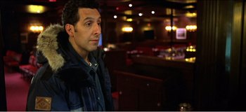 Movie still from “Fear X” (2003), directed by Nicolas Winding Refn – A man standing in front of a bar in a restaurant; Medium shot, High angle