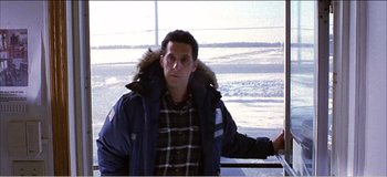 Movie still from “Fear X” (2003), directed by Nicolas Winding Refn – A man in a parka standing in front of some water; Medium shot, High angle