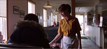 Movie still from “Fear X” (2003), directed by Nicolas Winding Refn – A woman standing in front of a person in a yellow shirt; Medium shot, Over the shoulder angle