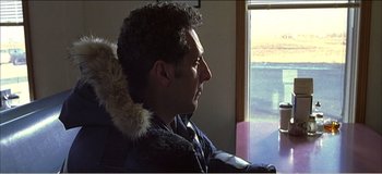 Movie still from “Fear X” (2003), directed by Nicolas Winding Refn – A man sitting in front of a window looking outside; Close Up shot, Over the shoulder angle