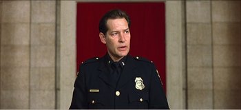 Movie still from “Fear X” (2003), directed by Nicolas Winding Refn – A man in a police uniform is standing in front of a red curtain; Close Up shot, Low angle