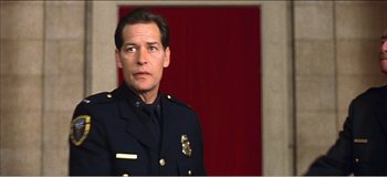 Movie still from “Fear X” (2003), directed by Nicolas Winding Refn – A man in a police uniform standing in front of a red curtain; Close Up shot, Low angle