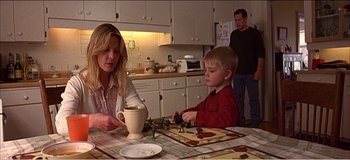 Movie still from “Fear X” (2003), directed by Nicolas Winding Refn – A woman and a child sitting at a table; Medium shot, Over the shoulder angle