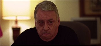 Movie still from “Fear X” (2003), directed by Nicolas Winding Refn – An older man is looking at the camera; Close Up shot, Low angle