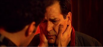 Movie still from “Fear X” (2003), directed by Nicolas Winding Refn – A person holding his head; Close Up shot, Over the shoulder angle