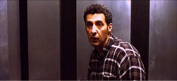 Movie still from “Fear X” (2003), directed by Nicolas Winding Refn – A person wearing a plaid shirt; Medium shot, Low angle