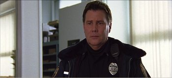 Movie still from “Fear X” (2003), directed by Nicolas Winding Refn – A police officer in a uniform is looking at the camera; Close Up shot, Low angle