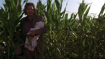 Movie still from “Fearless” (1993), directed by Peter Weir – A man holding a baby standing in a corn field; Medium shot, Low angle