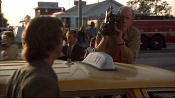 Movie still from “Fearless” (1993), directed by Peter Weir – A man taking a picture of another man in a taxi cab; Medium shot, Over the shoulder angle