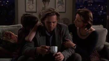 Movie still from “Fearless” (1993), directed by Peter Weir – A man sitting on a couch holding a coffee cup; Medium shot, Over the shoulder angle