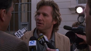 Movie still from “Fearless” (1993), directed by Peter Weir – A man with long blonde hair talking into a microphone; Close Up shot, Over the shoulder angle