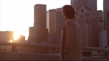 Movie still from “Fearless” (1993), directed by Peter Weir – A man standing in front of a city skyline at sunset; Wide shot, Low angle
