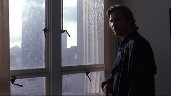 Movie still from “Fearless” (1993), directed by Peter Weir – A man standing in front of a window in the rain; Medium shot, Low angle