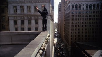 Movie still from “Fearless” (1993), directed by Peter Weir – A man standing on the side of a building on the edge of a ledge; Wide shot, High angle