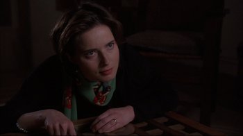 Movie still from “Fearless” (1993), directed by Peter Weir – A woman sitting at a table in a dark room; Close Up shot, High angle
