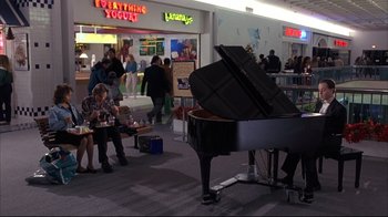 Movie still from “Fearless” (1993), directed by Peter Weir – People are sitting and standing around a black piano; Wide shot, High angle