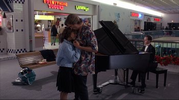 Movie still from “Fearless” (1993), directed by Peter Weir – A man and a woman kissing in front of a grand piano; Wide shot, Over the shoulder angle