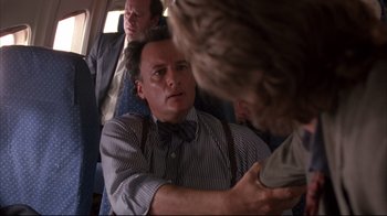 Movie still from “Fearless” (1993), directed by Peter Weir – A man in a bow tie and suspenders on a bus; Medium shot, Over the shoulder angle