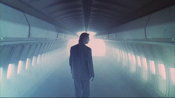 Movie still from “Fearless” (1993), directed by Peter Weir – A man in a suit is standing in a light tunnel; Wide shot, Low angle