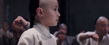 Movie still from “Fearless” (2006), directed by Ronny Yu – A boy with a shaved head is looking into the distance; Close Up shot, Over the shoulder angle