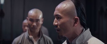 Movie still from “Fearless” (2006), directed by Ronny Yu – A man with a shaved head and a mustache; Close Up shot, Over the shoulder angle