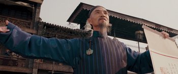 Movie still from “Fearless” (2006), directed by Ronny Yu – An older man wearing a hat and a blue and black shirt; Medium shot, Low angle