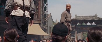 Movie still from “Fearless” (2006), directed by Ronny Yu – An old man standing in front of a group of people; Medium shot, Over the shoulder angle