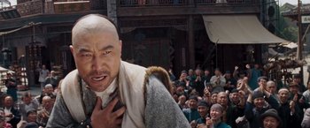 Movie still from “Fearless” (2006), directed by Ronny Yu – A man with a shaved head and a beard in front of a group of people; Close Up shot, Low angle