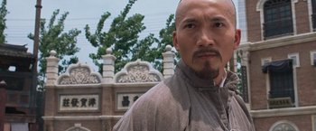 Movie still from “Fearless” (2006), directed by Ronny Yu – A man with a bald head standing in front of a building; Close Up shot, Low angle