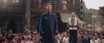 Movie still from “Fearless” (2006), directed by Ronny Yu – An older man in a blue and black outfit standing in front of a crowd; Medium shot, Low angle