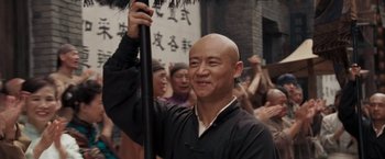 Movie still from “Fearless” (2006), directed by Ronny Yu – A man holding an umbrella in front of a group of onlookers; Close Up shot, Low angle