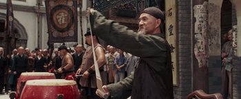 Movie still from “Fearless” (2006), directed by Ronny Yu – An older man holding a sword in front of a group of people; Medium shot, Over the shoulder angle