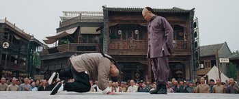 Movie still from “Fearless” (2006), directed by Ronny Yu – A man kneeling down on the ground in front of a crowd; Wide shot, Low angle