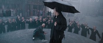 Movie still from “Fearless” (2006), directed by Ronny Yu – A man holding an umbrella in front of a group of people; Wide shot, High angle