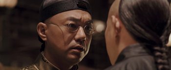 Movie still from “Fearless” (2006), directed by Ronny Yu – A person wearing glasses and a hat; Close Up shot, Over the shoulder angle