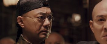 Movie still from “Fearless” (2006), directed by Ronny Yu – An older man wearing glasses and a hat; Close Up shot, Over the shoulder angle