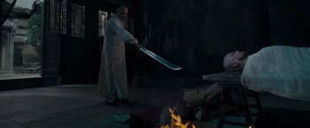 Movie still from “Fearless” (2006), directed by Ronny Yu – A man holding a sword in front of a fire pit; Medium shot, High angle