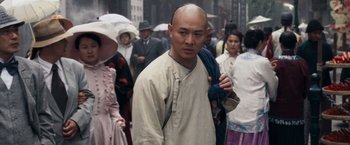 Movie still from “Fearless” (2006), directed by Ronny Yu – A man with a shaved head walks through a crowd of people; Close Up shot, Over the shoulder angle