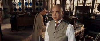 Movie still from “Fearless” (2006), directed by Ronny Yu – A man in a vest and tie standing in front of another man; Medium shot, Over the shoulder angle