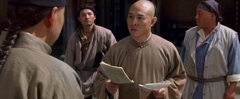 Movie still from “Fearless” (2006), directed by Ronny Yu – A man with a bald head holding a book and another man with a bald head holding a book; Medium shot, Over the shoulder angle