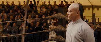 Movie still from “Fearless” (2006), directed by Ronny Yu – A man standing in front of a crowd of people; Medium shot, Over the shoulder angle